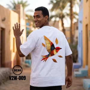 DEDO V2W-009 white oversized t-shirt with an artistic flying bird graphic in an outdoor village setting.