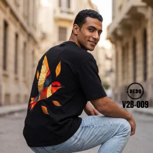 Man crouching on an old city street, glancing over his shoulder in a black DEDO oversized t-shirt with a back geometric flying bird graphic, item code V2B-009.