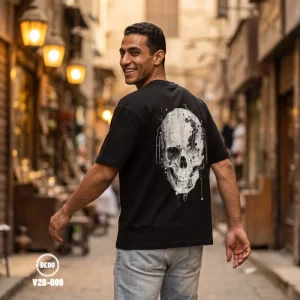 Man wearing a black DEDO oversized T-shirt with a futuristic skull graphic in a traditional Cairo street